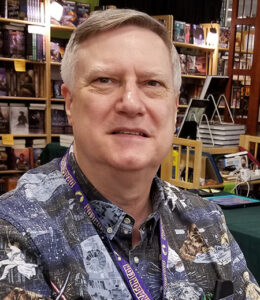 A headshot of the author, in front of a bookshelf