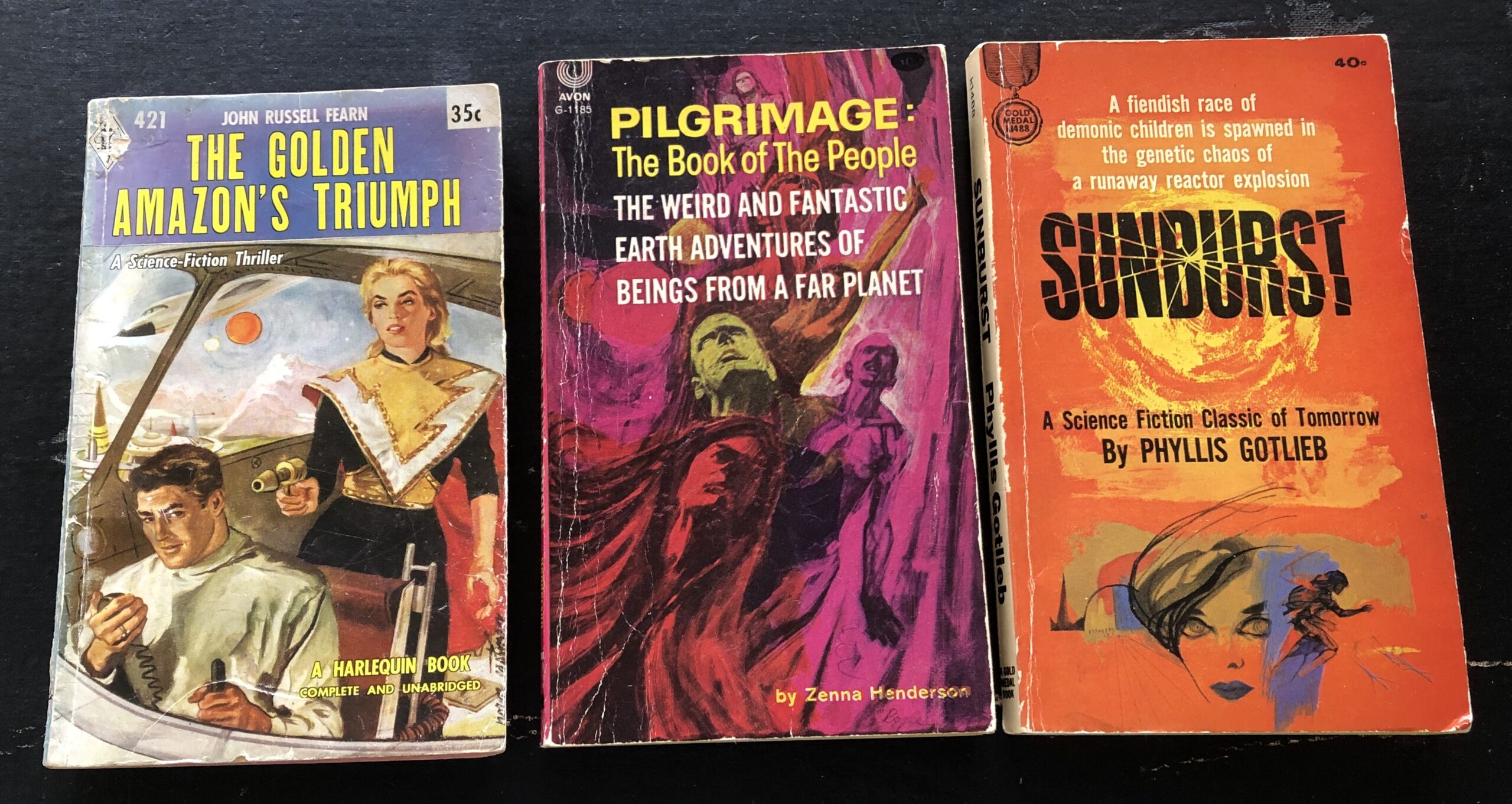 From left to right: The Golden Amazon’s Triumph by John Russell Fearn, 1958, Harlequin Books, cover art uncredited; Pilgrimage: The Book of the People by Zenna Henderson, 1961, Avon reprint of Doubleday hardcover, cover art uncredited; and Sunburst by Phyllis Gotlieb, 1964, Fawcett Gold Medal original (developed from shorter version published in Amazing Magazine), cover art uncredited. Photo by Rosemary Jones, from the author’s collection.