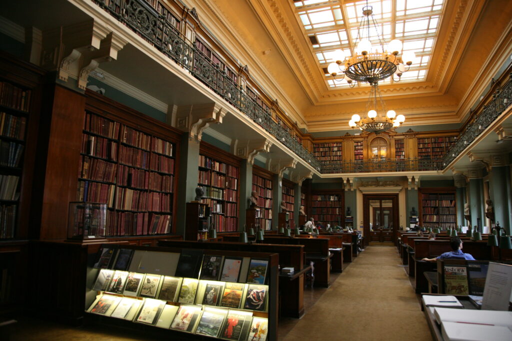 Interior of Victoria and Albert Museum Library in London. Rows of reading pews lined by bookshelves.